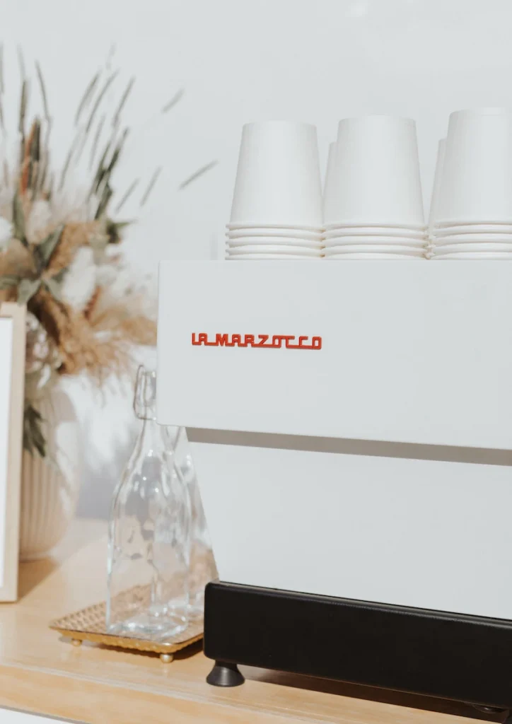 A white espresso machine with cups on top