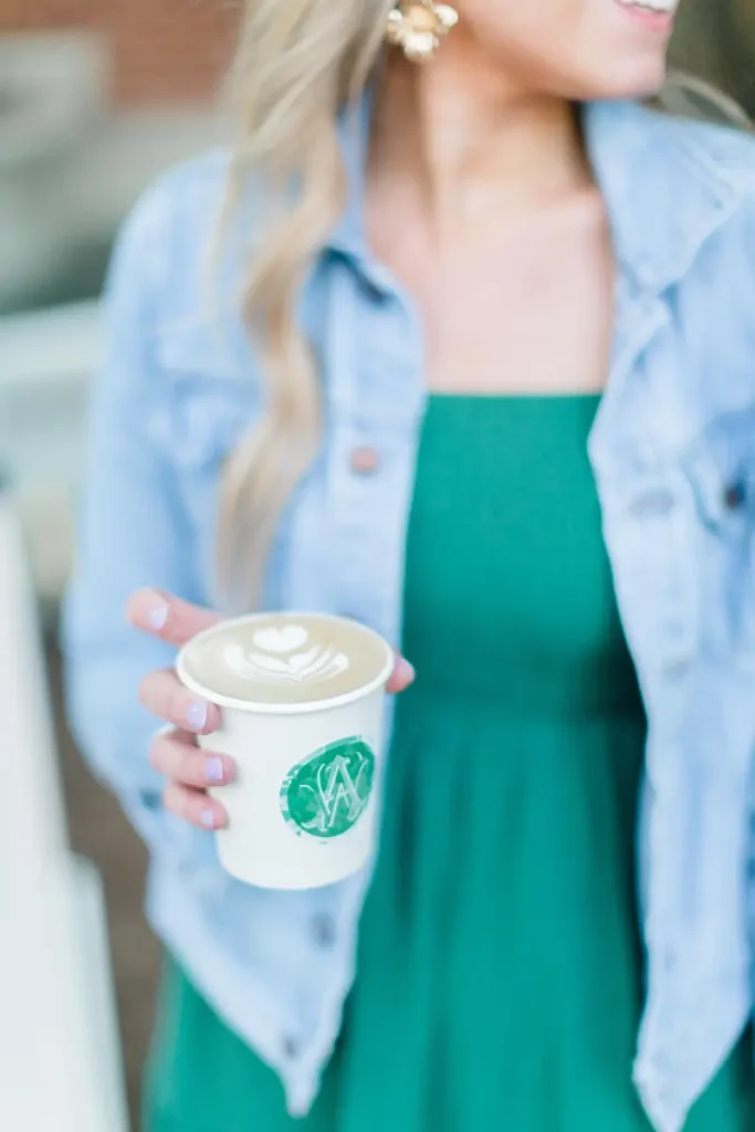 A woman holding a latte with custom a custom Roaming Spirts Coffee cup