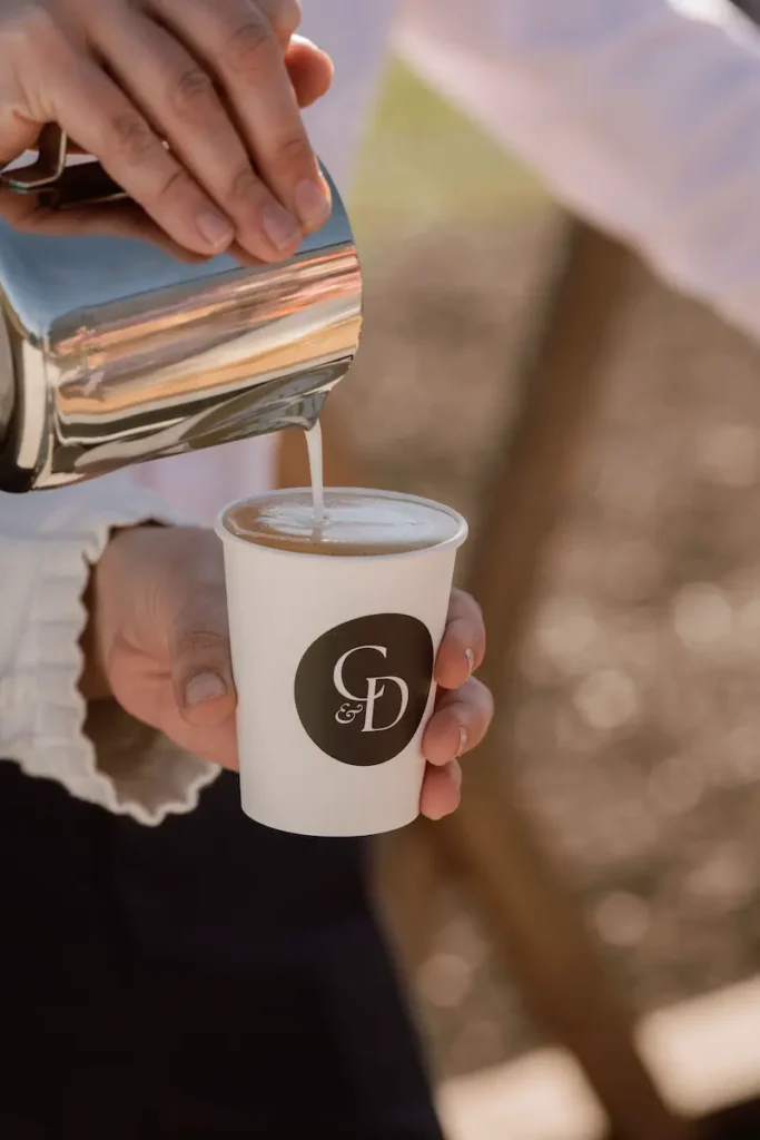 Barista making latte art in a custom Roaming Spirits Coffee cup