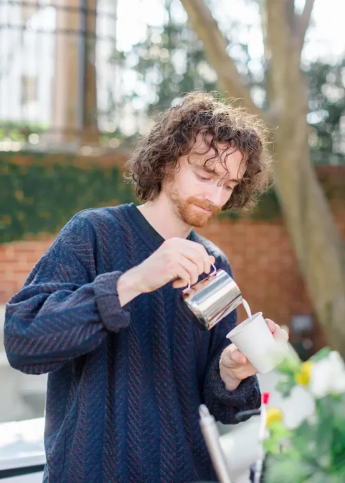 A barista pouring milk into a cup